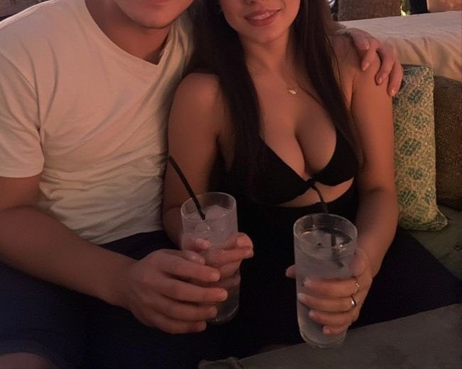 Sitting close together, the girlfriend and boyfriend exchange a playful smile, their bodies touching in a cozy and intimate moment, full of electric chemistry.